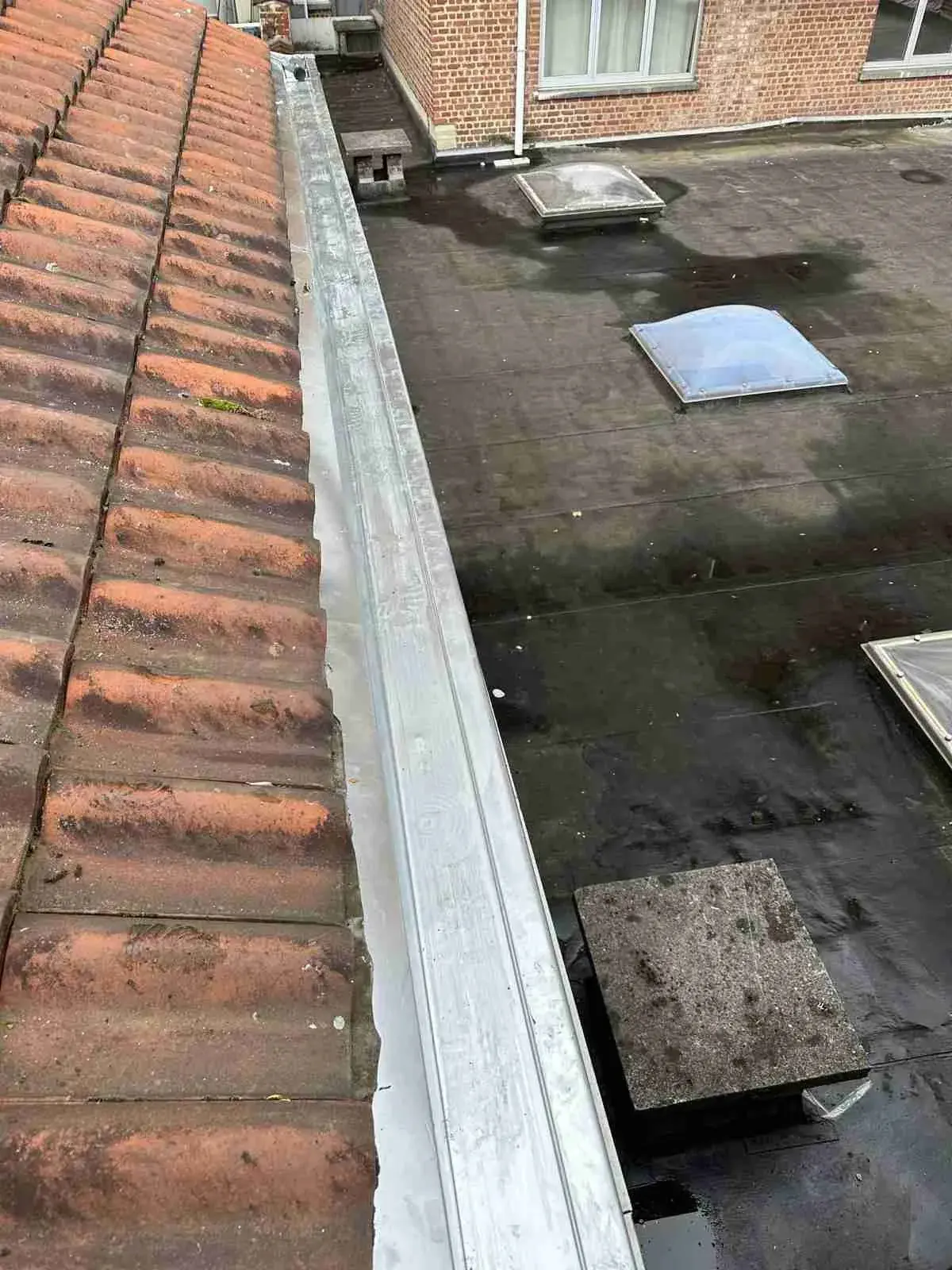 Toit plat gravillonné avec coupole, bordé d’une rive en zinc et de tuiles rouges