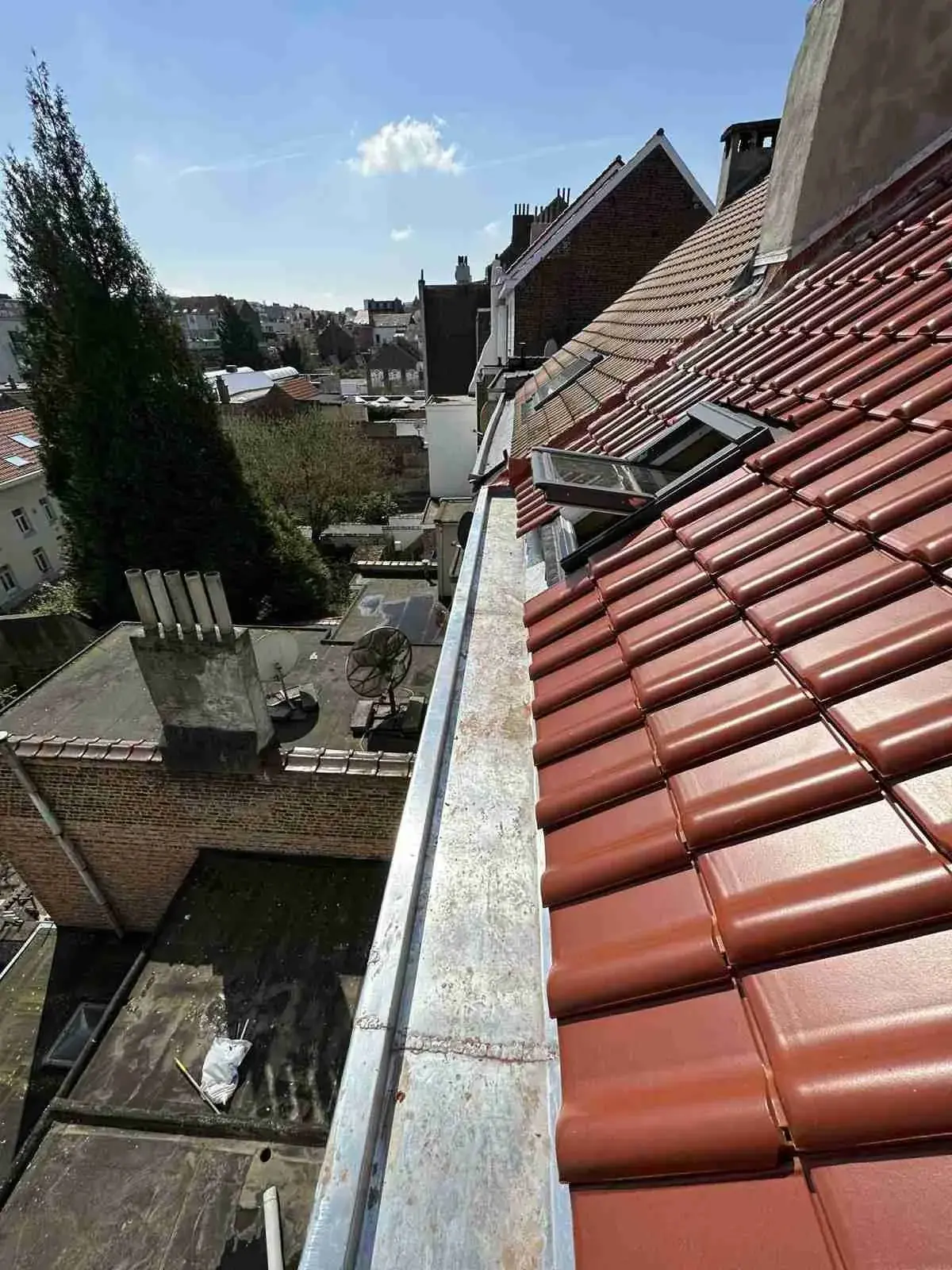 Tuiles rouges et gouttière en zinc vues depuis le toit