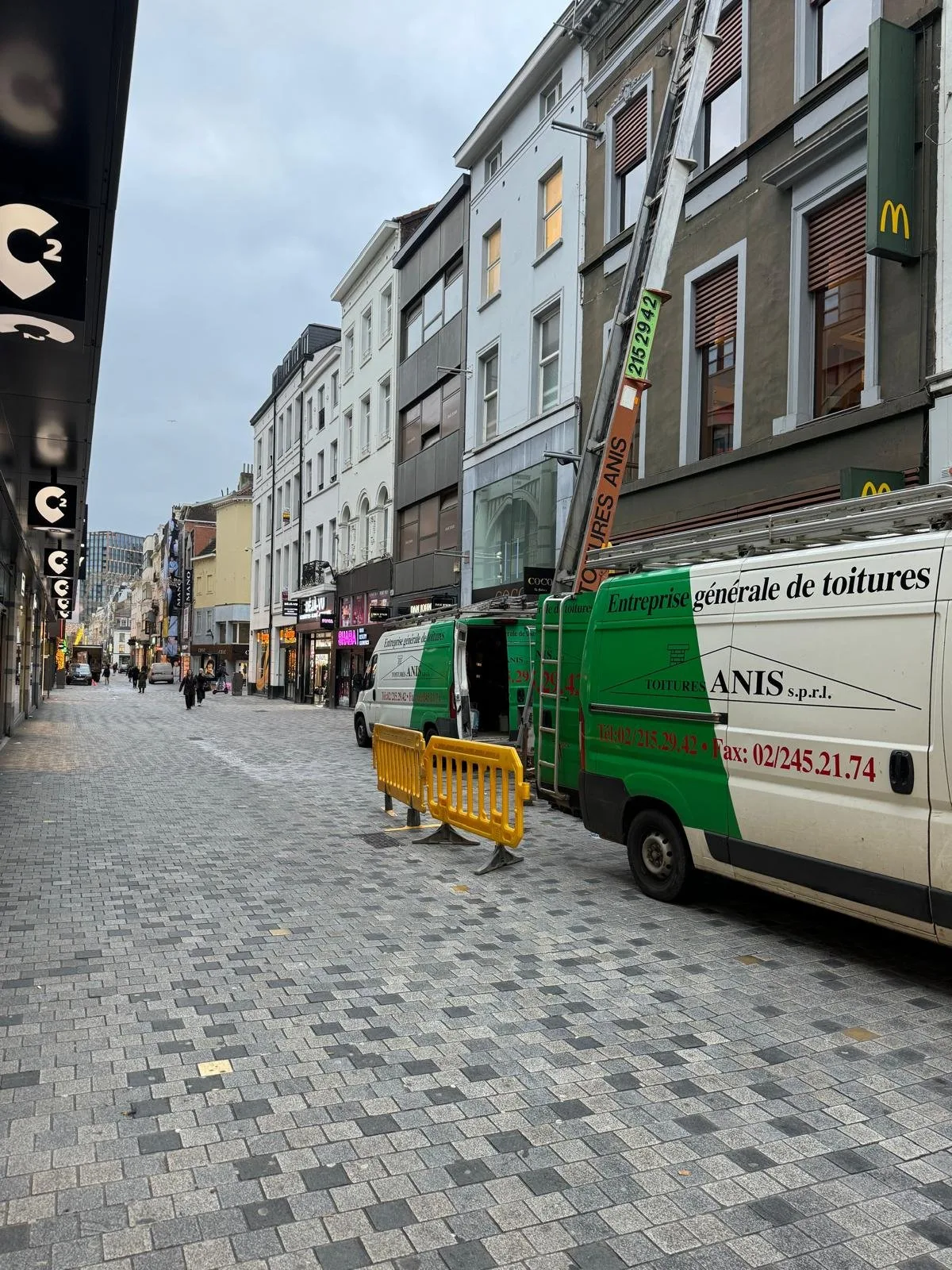 Rue commerçante avec la camionnette Anis Toitures stationnée devant le chantier