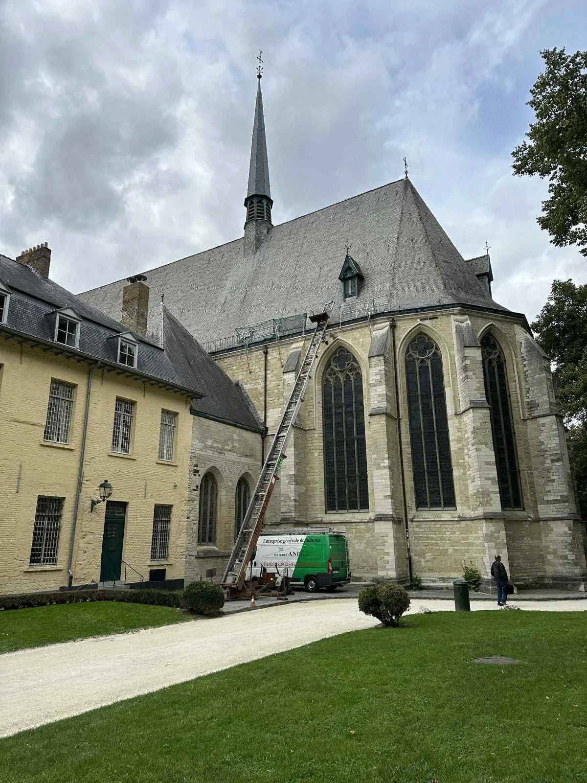 Église avec toit en tuiles rouges et échelle de couvreur dressée contre la nef