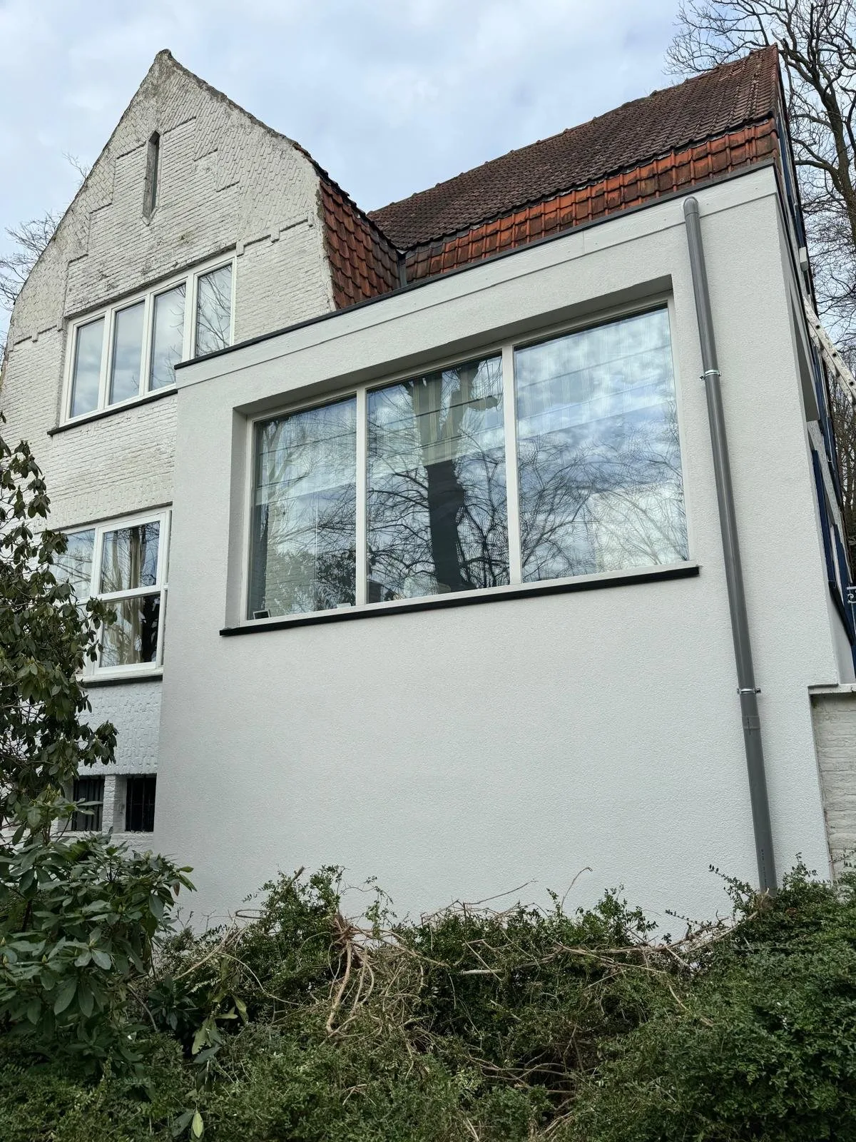 Extension blanche avec grandes baies vitrées et toiture plate
