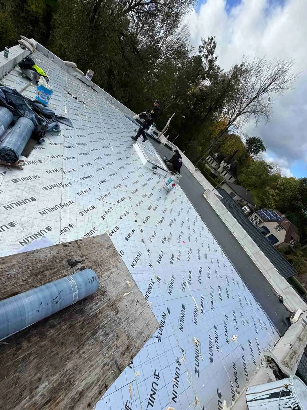 Travaux d'isolation de toiture, ouvriers en gilets jaunes, membrane NITINOL blanche